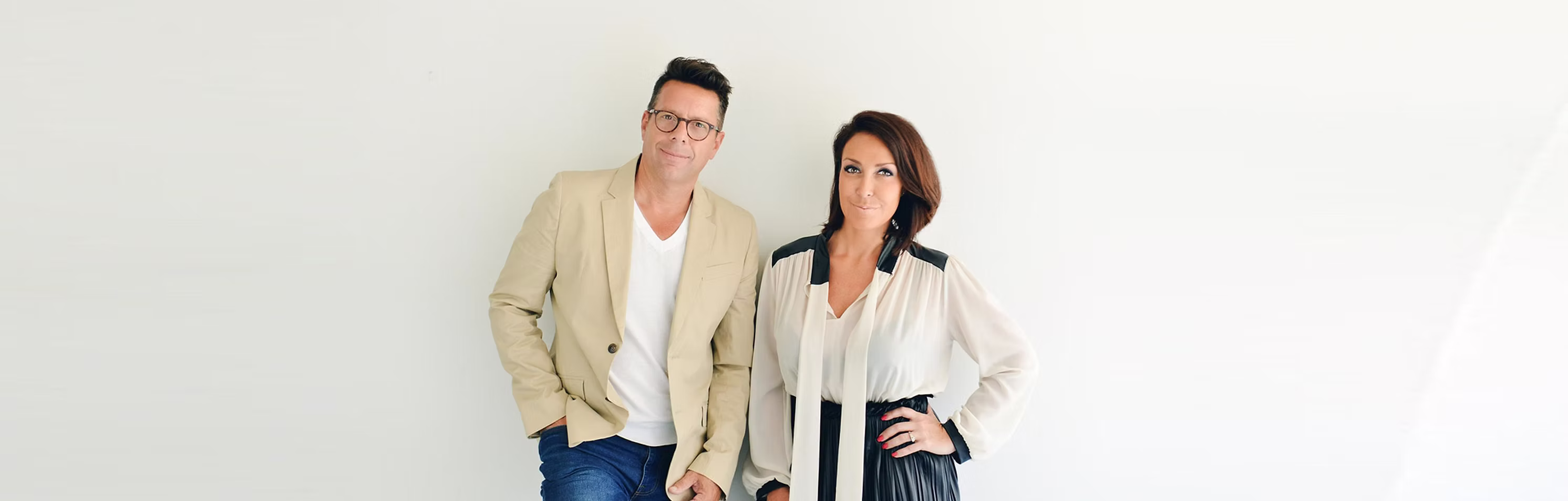 Sylvain Duguay en veston beige et Geneviève Bellavance en blouse blanche et noire, debout devant un mur clair.